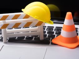 Road,Barrier,With,Hard,Hat,And,Traffic,Cone,On,Laptop