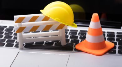 Road,Barrier,With,Hard,Hat,And,Traffic,Cone,On,Laptop